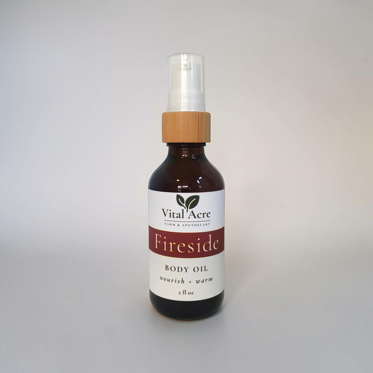 Vital Acre Farm & Apothecary Fireside nourishing body oil in a brown glass bottle with a wooden pump dispenser.