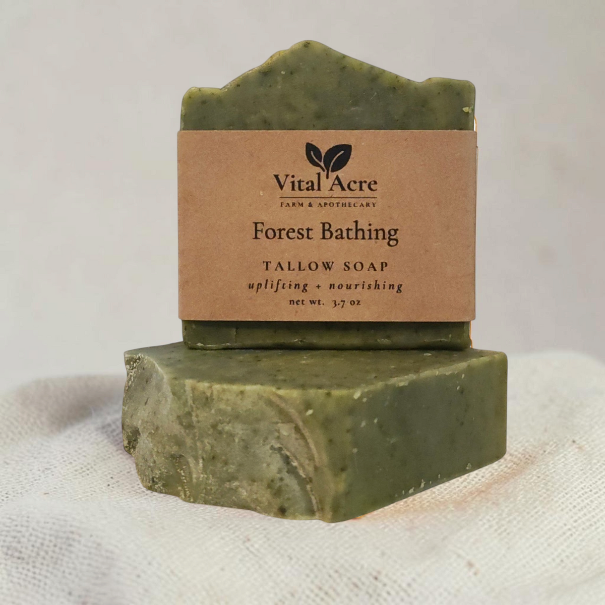 Vital Acre Farm & Apothecary Forest Bathing tallow soap bar with a rustic kraft paper label on a textured cloth.