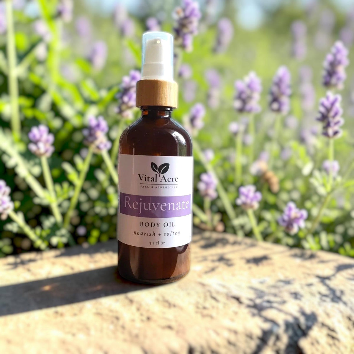 Vital Acre Farm & Apothecary REjuvenate body oil in an amber glass bottle with a pump, set against blooming lavender.