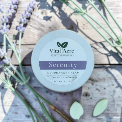 Vital Acre Farm & Apothecary Serenity deodorant cream in a round tin with lavender sprigs on a rustic wooden surface.