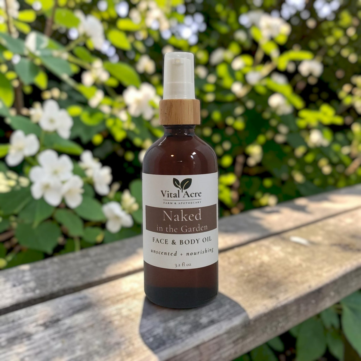 Vital Acre Farm & Apothecary Naked in the Garden unscented face and body oil in a glass bottle on a wooden bench.